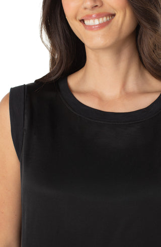 Woman wearing a black sleeveless top with a plain background