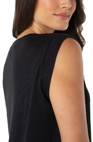 Black sleeveless top worn by a person on a white background