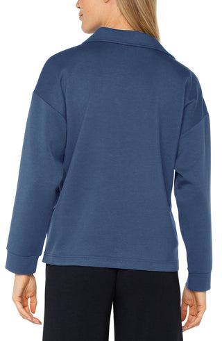 A woman wearing a blue V-neck popover with long sleeves and a collar.