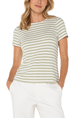 A woman wearing a striped crew neck knit tee in green and cream colors, paired with white pants.