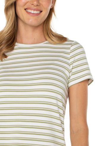 A woman wearing a striped crew neck knit tee in green and cream colors, paired with white pants.