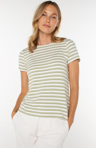 A woman wearing a striped crew neck knit tee in green and cream colors, paired with white pants.