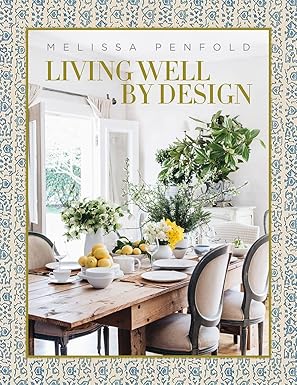 The cover of the book 'Living Well by Design' by Melissa Penfold features a photograph of a well-laid out dining table with chairs around it, decorated with flowers and table settings, in a room with a large window and white walls. Living Well by Design.