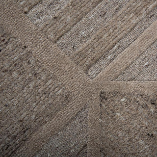 Lofton 7'9"x9'9" Rug in Brown
A rectangular area rug with a geometric pattern of interlocking triangles and rectangles in shades of taupe, beige, and brown, showing a textured woven surface.