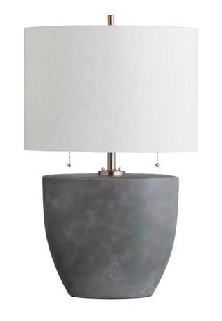 A modern table lamp with a gray ceramic base and a white linen shade, featuring two pull chains and a bronze-colored metal mount.