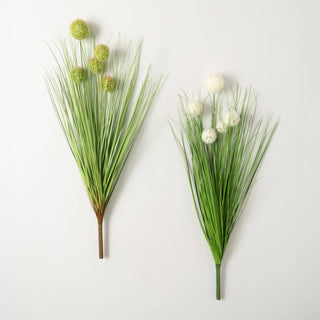 Two artificial onion grass bushes with green stalks and either green or cream seed pods, displayed against a white background.