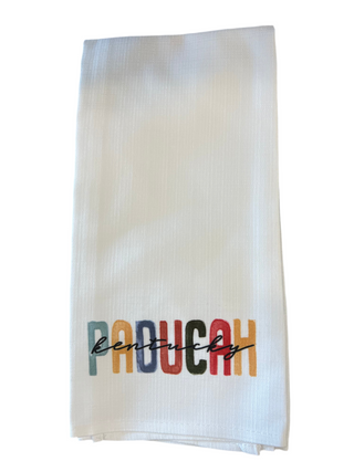 White towel with 'Paducah, Kentucky' printed in colorful letters on a white background, Paducah Poster Tea Towel in Earth Tones