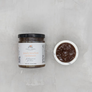 A jar of Peach Bourbon Cardamom Fruit Preserves next to an open container of the preserves, both on a light grey surface, finch and fennel 