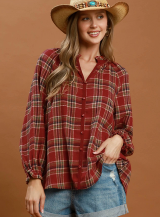 Plaid Button Down Long Sleeve Relaxed Top in Red
A woman wearing a red and beige plaid button-up shirt with long balloon sleeves, styled with a straw cowboy hat and blue denim shorts against a solid brown background.