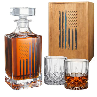 Whiskey decanter and glasses with wooden box featuring American flag design on a white background. Police Tactical Blue Tattered American Flag Whiskey Decanter Set with Two Glasses