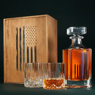 Whiskey decanter and glasses with wooden box featuring American flag design on a dark background. Police Tactical Blue Tattered American Flag Whiskey Decanter Set with Two Glasses
