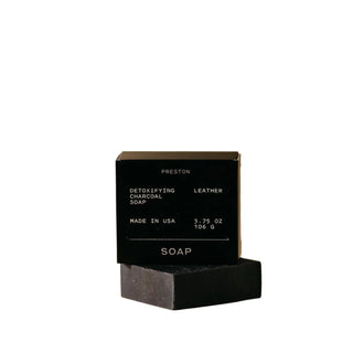 A black bar of soap labeled 'PRESTON' with the scent 'Leather' written on it. The packaging also includes the text 'Detoxifying Charcoal', 'Made in USA', and indicates the soap weight as 3.