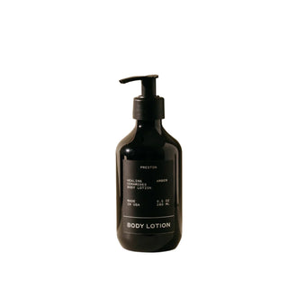 A black pump bottle of Preston body lotion labeled 'BODY LOTION' with white text, indicating the scent as 'Amber'.