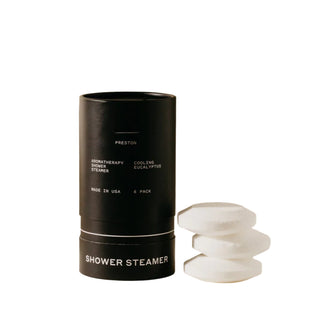 Preston brand shower steamer with cooling eucalyptus, displayed in a cylindrical black container with white tablets stacked in front.