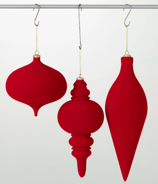 Three red Christmas ornaments hanging on a rod against a white background