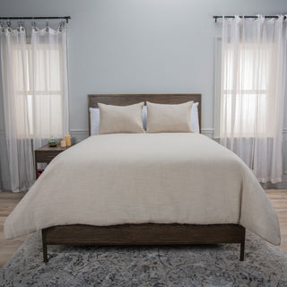 Rizzy Blackberry Grove Comforter Set in Natural
A neatly made bed in a styled bedroom, covered with a light beige linen-textured comforter and two matching beige pillows linen