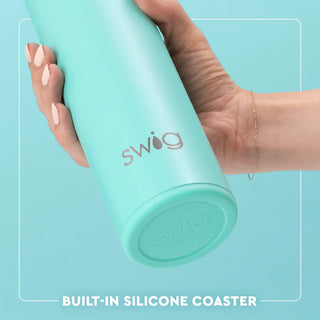Hand holding a mint green Swig tumbler with a light blue background