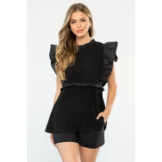 Woman wearing a  THML Ruffle Textured Top, Black a white background