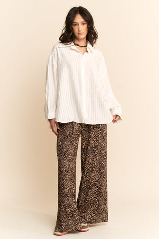 Woman wearing a white blouse and leopard print pants against a beige background. Taupe Leopard Printed Wide Leg Pants