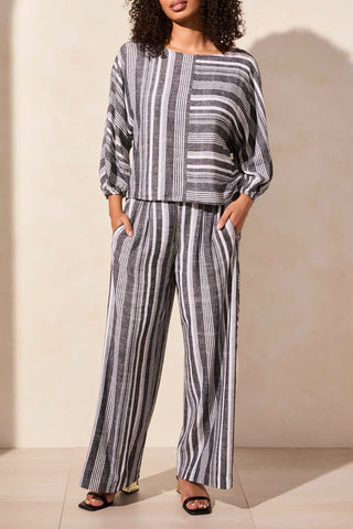 A woman wearing a black and white striped tribal boat neck blouse with dolman sleeves.