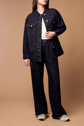 A person wearing Tribal Brooke Hugging Wide Trouser Jeans in a dark rinse color, with a high-rise waist and wide leg design, paired with a white top and beige shoes.
