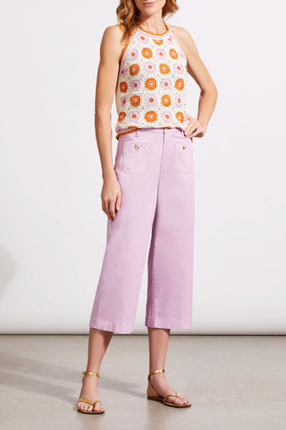 A model wearing wide leg crop jeans in an orchid color with double button pockets. The model paired the jeans with a colorful embroidered top.
