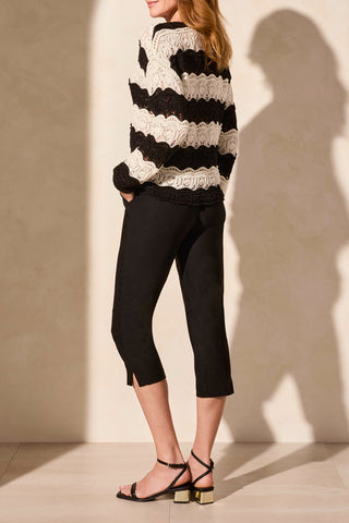 A woman wearing a long sleeve V-neck crochet swirl stripe sweater in black and cream.