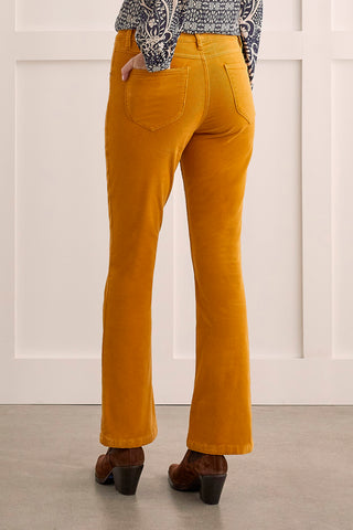 A model wearing suede pants in a marigold color paired with brown boots and a geometric top.