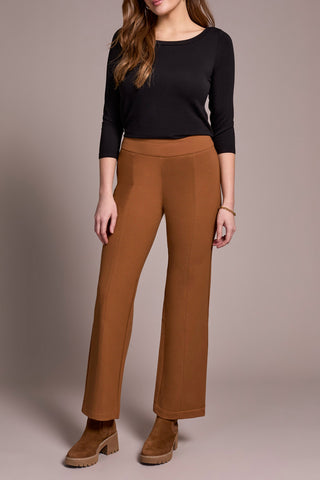 Woman wearing a black top and brown pants on a neutral background