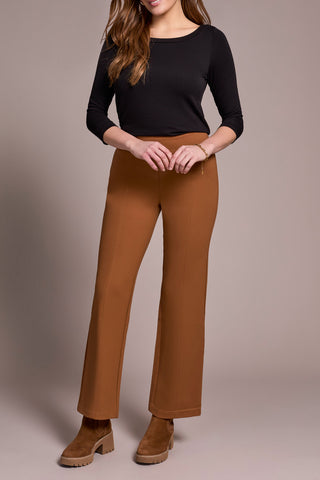 Person wearing a black top and brown pants on a beige background