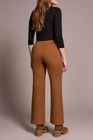 Woman wearing brown flared pants and a black top against a beige background