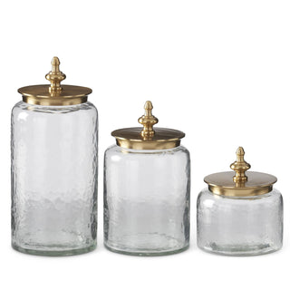 Assorted clear glass jars with gold lids on a white background. Wavy Glass Containers with Gold Metal Finial Lid Assorted