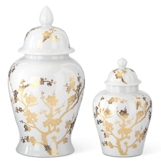 Two white ceramic jars with gold floral patterns and lids on a white background