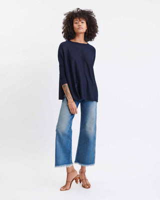 Woman wearing a navy sweater and blue jeans on a white background. Mersea Catalina Crewneck Sweater in Navy