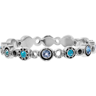 A silver-toned stretch bracelet featuring scalloped links and oval bezel-set blue stones, some surrounded by small black accent stones, shown on a plain white background. Brighton Halo Burst Hinged Bangle
