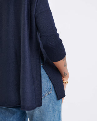 Person wearing a navy sweater and blue jeans on a white background. Mersea Catalina Crewneck Sweater in Navy