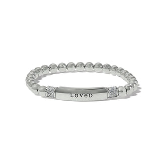 A silver-colored bracelet with the word 'LOVED' engraved on it, displayed against a white background. Brighton