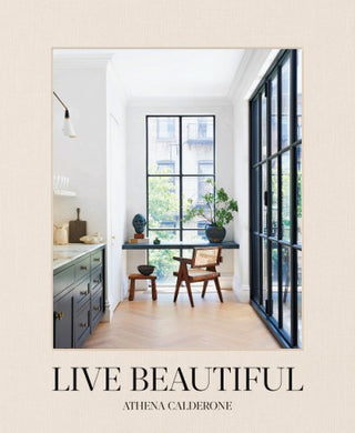 Cover of the 'Live Beautiful' book by Athena Calderone, featuring a photograph of a bright, well-designed interior space with large windows, wooden flooring, and stylish furniture. Live Beautiful Book.